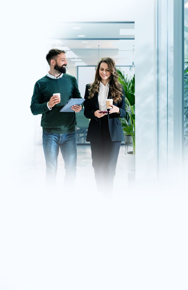 Zwei Mitarbeitende mit Tablet und Kaffee im Büro